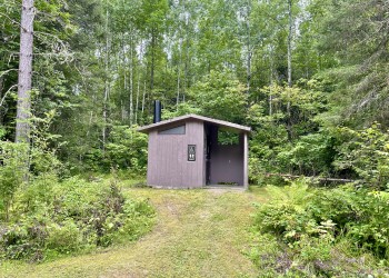 photo of a vaulted toilet structure in the forest