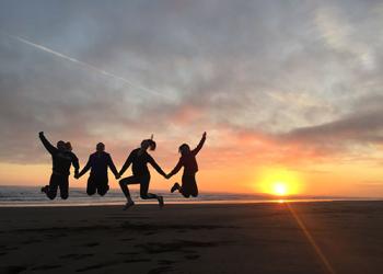4 dark silhouettes with bright orange sunset in the background
