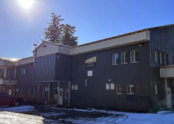 dark brown building with light tan at top, snow on ground, red vehicle 