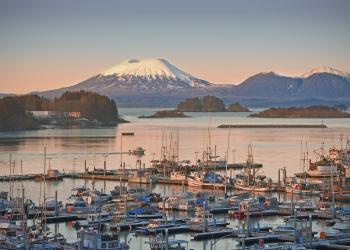 Dozens of boats dock in a mountainous harbor.