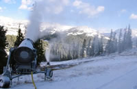 Snow making machines producing snow at a ski area.