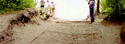 Photo of people pulling a small boat out of water onto a wooden boat ramp structure.