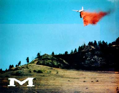 A photo of a slurry bomber dumping retardant on Mount Sentinal above the M.
