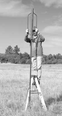[photo] Man on latter using fence post driver.