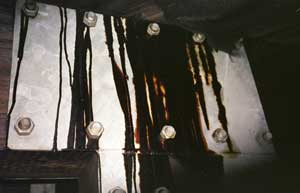 photo of colled aphalt dripping from the underside of a bridge