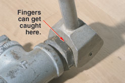 Image of a hydrant handle with an arrow pointing to a section where the handle and shaft connect.  The text by the arrow reads: Fingers can get caught here.
