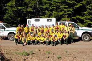 Photo of a fire crew posing for a picture in front of a fire truck.