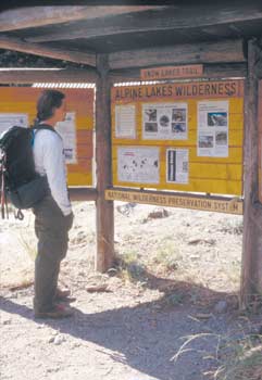 Photo of a hiker reading information off of a bulletin board at Snow Lakes Trail at Alpine Lakes Wilderness.