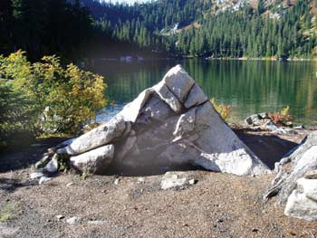 Photo of campfire scarred on the shore of a mountain lake.