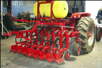 Image of an Egedal shielded herbicide sprayer hitched to the back end of a tractor.