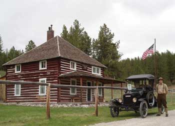 Photo of a ranger standing in front of an old model auto in front of the Judith River Ranger Station.