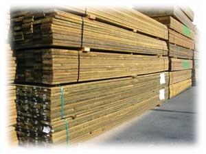 Photo of pressure treated lumber stacked on a concrete slab.