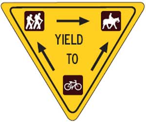 Illustration of a sign demonstrating trail right-of-way. On the sign the text reads, Yield To.