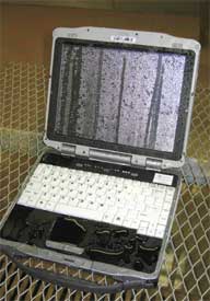 Photo of an open laptop that has just gone through a rain/moisture test and is covered with water.
