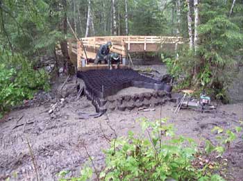 Photo of a person installing a geocell on a trail bridge approach.
