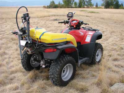 Photo of an ATV equiped with a herbicide sprayer in the middle of a field.