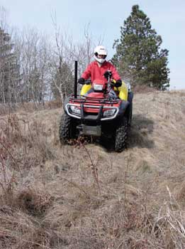 Photo of a person on an ATV driving down a steep slope.