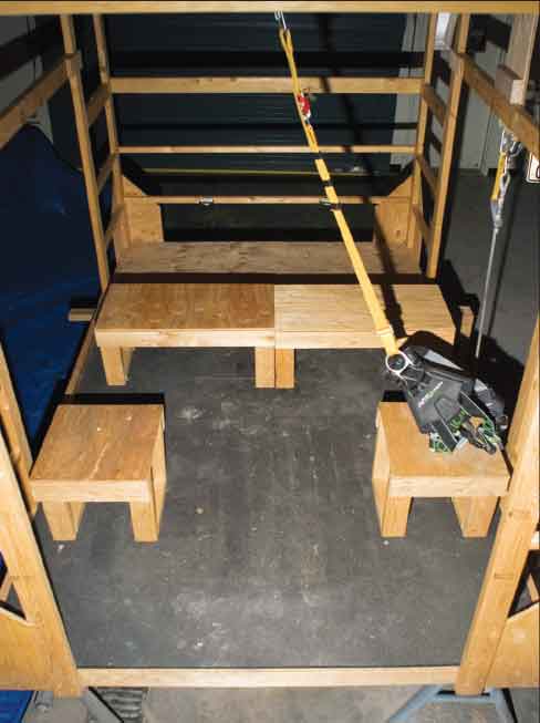 A wooden helicopter simulator cabin assembled in a large garage.