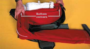 Photo of a man performing the first S-fold that fills the bottom corners. In the photo the text reads, bottom corners.