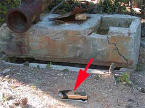 Photo of a radioisotope device laying on the ground with a red arrow pointing to it.