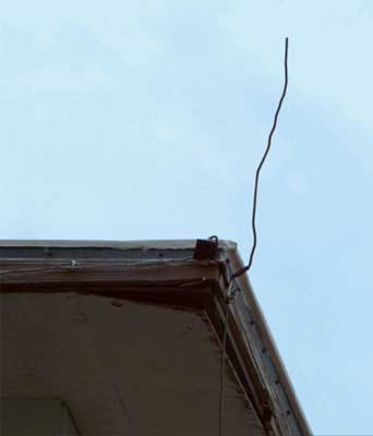 Photo of the edge of a roof with wire sticking up into the sky. 
