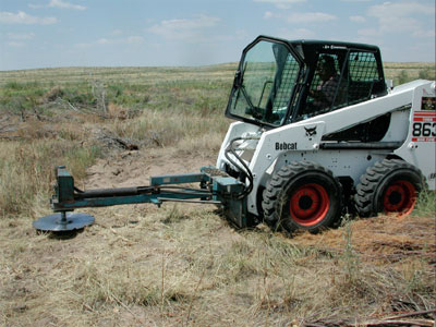Photo of a Bobcat with a brush saw attached.