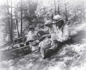 Phot of firefighters siting on a hillside eating.