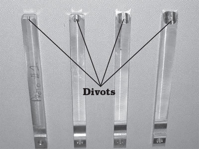 Photo of different sizes of rams used for the Seed Stick. In the photo, there is a label that reads, Divots, and arrows pointing to the part on each ram.