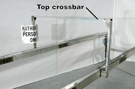 Photo of the rails where the center rail uprights are attached along with the top crossbar which is attached to the center rail uprights. In the photo the text names the parts of the equipment, which reads, top crossbar.