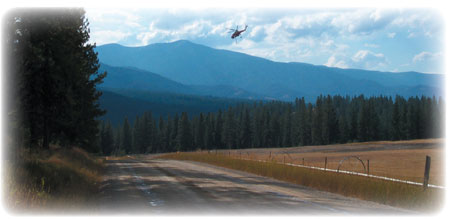 Photo of a helicopter that is flying over a roadway.