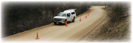 Photo of a truck stopped along a dirt road with cones setup around it.