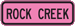 Pink rectangular sign with the text, Rock Creek.