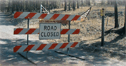 Photo of a three-tiered barricade with a sign on the middle tier that reads, Road Closed.