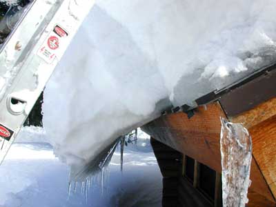 Closeup photo of a ladder leaning against the snow-covered roof of the Visitor Center